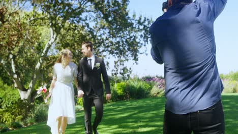 Photographer-taking-photo-of-bride-and-groom-walking-holding-hands-4K-4k