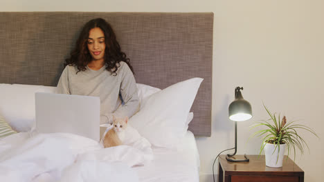 Woman-using-her-laptop-while-sitting-on-bed-with-her-cat-4K-4k