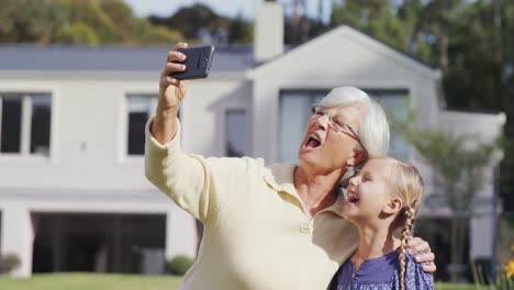 Grandmother-and-little-girl-making-funny-faces-while-taking-selfie-4K-4k