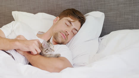 Young-man-sleeping-on-bed-holding-cat-in-his-arms-4K-4k