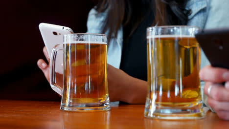 Mittelteil-Der-Freunde,-Die-Ihr-Mobiltelefon-Benutzen,-Während-Sie-Bier-Trinken,-4k