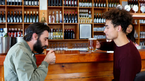 Male-friend-interacting-while-having-beer-at-counter-4k
