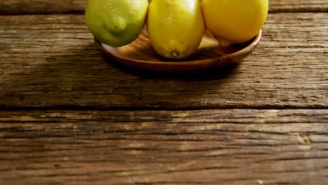 Zitronen-Auf-Einem-Teller-Auf-Einem-Holztisch-4k