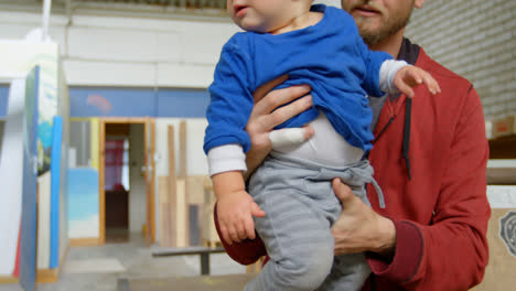Man-holding-his-son-in-workshop-4k