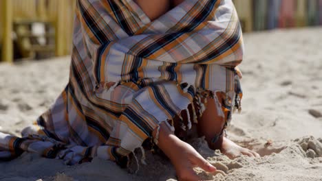 Teenage-girl-wrapped-in-blanket-playing-with-sand-4k
