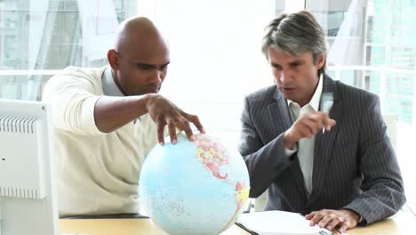 Two-ambitious-businessmen-looking-at-a-terrestrial-globe