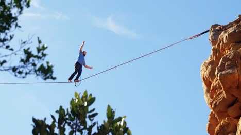Highline-athlete-balancing-on-slackline-in-rocky-mountain-4k