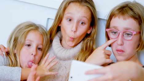 Siblings-taking-selfie-with-mobile-phone-in-bedroom-4k