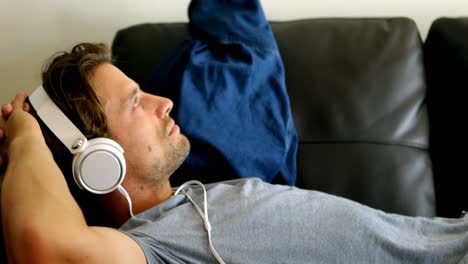 Man-listening-music-on-headphones-living-room-4k