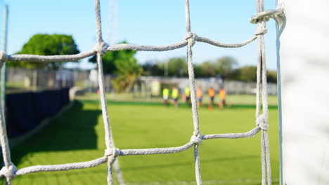 Goalpost-net-and-soccer-players-running-4k