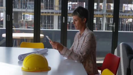 Female-engineer-using-mobile-phone-at-desk-4k