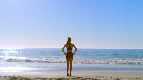 Fit-woman-standing-with-hands-on-hip-in-the-beach-4k