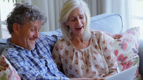 Senior-couple-discussing-over-laptop-on-sofa-4k