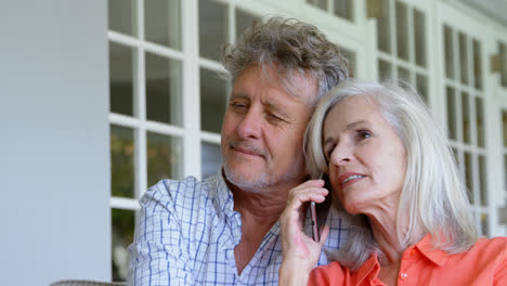 Senior-woman-talking-on-mobile-phone-next-to-her-man-on-sofa-4k