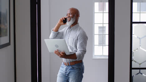 Businessman-talking-on-mobile-phone-while-using-laptop-4k