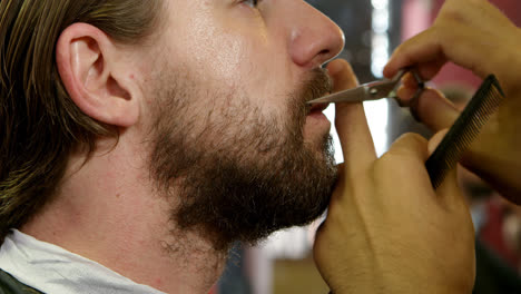 Man-getting-his-beard-trimmed-with-scissors-4k