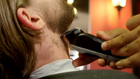 Man-getting-his-beard-trimmed-with-trimmer-4k