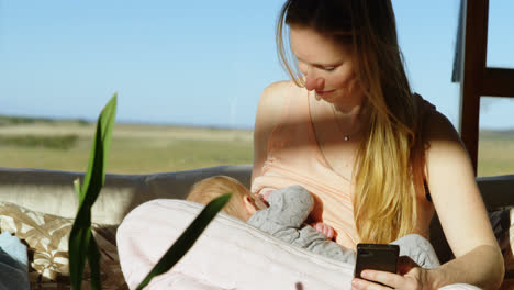Mutter-Stillt-Ihr-Baby,-Während-Sie-Ihr-Mobiltelefon-In-4K-Nutzt