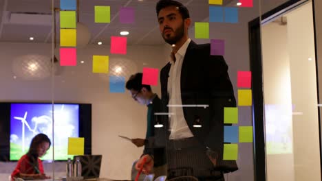 Businessman-looking-at-sticky-notes-in-office-4k