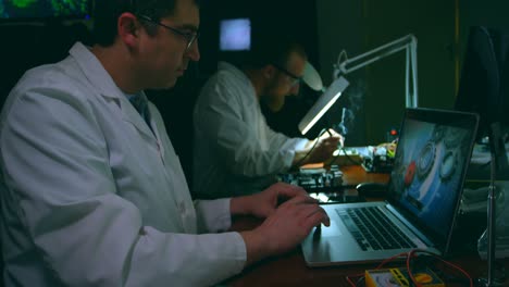 Male-robotic-engineer-using-laptop-at-desk-4k