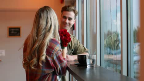 Young-man-giving-rose-to-woman-in-cafe-4k