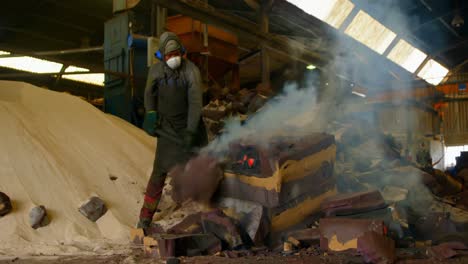 Worker-breaking-hot-mold-in-foundry-workshop-4k