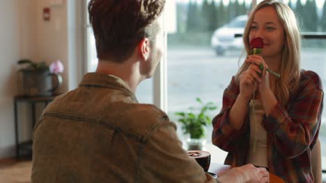 Young-man-giving-rose-to-woman-in-cafe-4k