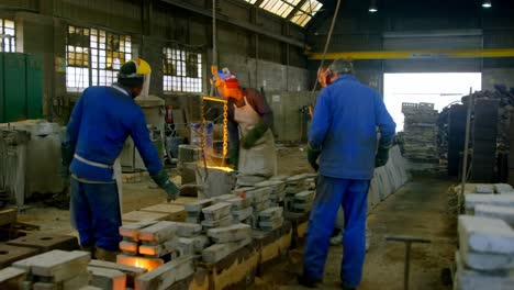 Workers-pouring-molten-metal-in-molds-at-workshop-4k