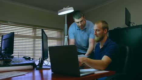 Male-robotic-engineers-discussing-over-laptop-at-desk-4k