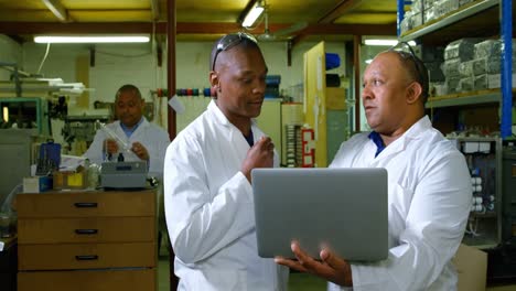 Male-workers-discussing-over-a-laptop-in-glass-factory-4k