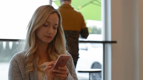 Beautiful-woman-using-mobile-phone-in-cafe-4k
