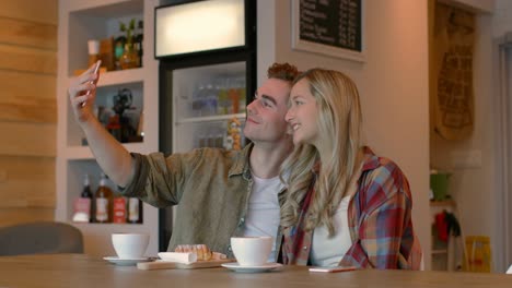 Young-couple-taking-selfie-on-mobile-phone-in-cafe-4k