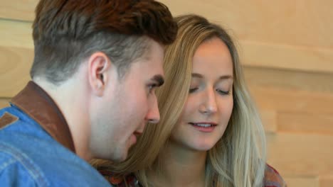 Close-up-of-young-couple-using-mobile-phone-in-cafe-4k