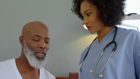 Low-angle-view-of-young-mixed-race-doctor-discussing-medical-reports-with-mature-man-at-home-4k