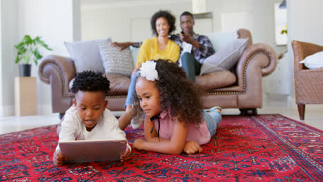 Vorderansicht-Süßer-Schwarzer-Kinder,-Die-Im-Wohnzimmer-Eines-Komfortablen-Zuhauses-Ein-Digitales-Tablet-Nutzen,-4K