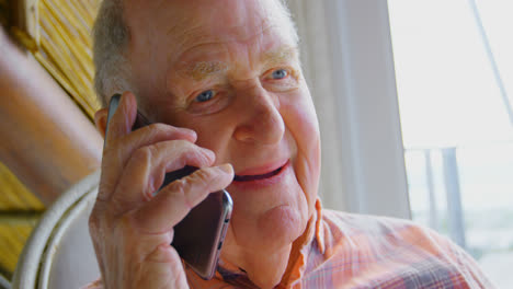 Close-up-of-Caucasian-senior-man-talking-on-mobile-phone-in-a-comfortable-home-4k
