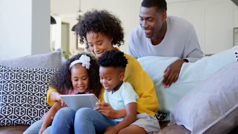 Vista-Frontal-De-Una-Familia-Negra-Usando-Una-Tableta-Digital-En-La-Sala-De-Estar-De-Casa-4k