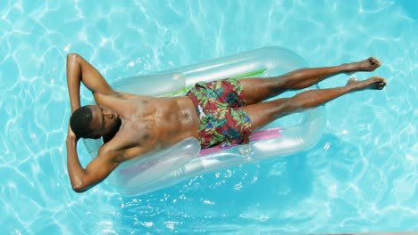 High-angle-view-of-young-black-man-relaxing-on-inflatable-raft-in-the-swimming-pool-4k
