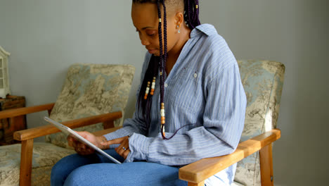 Seitenansicht-Einer-Jungen-Schwarzen-Frau,-Die-Im-Wohnzimmer-Eines-Komfortablen-Zuhauses-Ein-Digitales-Tablet-Nutzt,-4K
