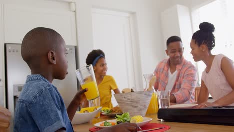 Front-view-of-happy-black-family-eating-food-on-dining-table-in-a-comfortable-home-4k