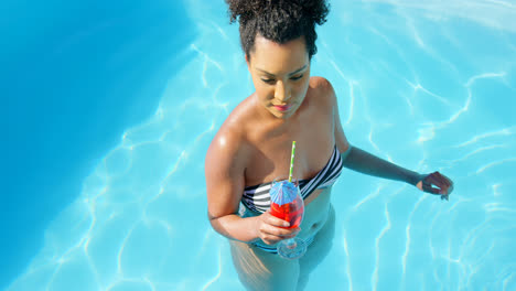High-angle-view-of-young-mixed-race-woman-drinking-cocktail-in-swimming-pool-4k