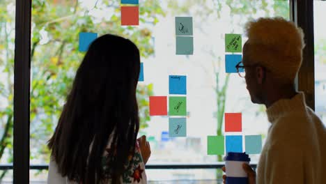 Rear-view-of-young-mixed-race-business-colleagues-discussing-over-sticky-notes-in-modern-office-4k