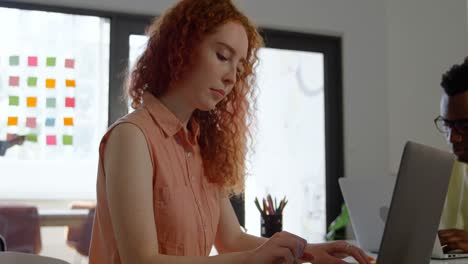 Side-view-of-young-caucasian-businesswoman-working-on-laptop-in-a-modern-office-4k