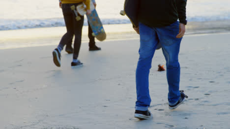 Rear-view-of-young-caucasian-friends-walking-together-at-the-beach-during-sunset-4k