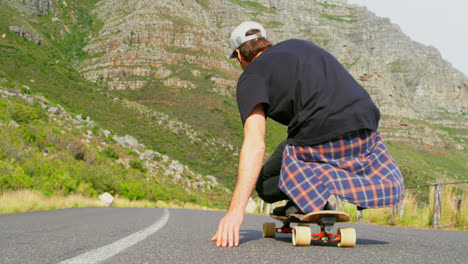 Rear-view-of-cool-young-man-riding-on-skateboard-on-downhill-at-countryside-road-4k