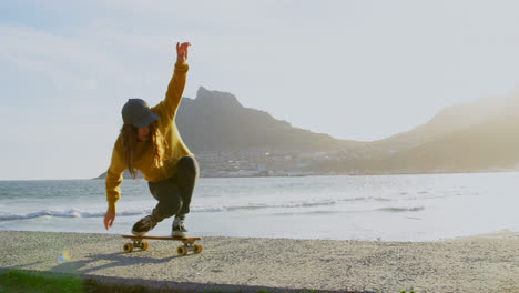 Front-view-of-young-caucasian-woman-practicing-skateboard-trick-on-the-pavement-at-beach-4k