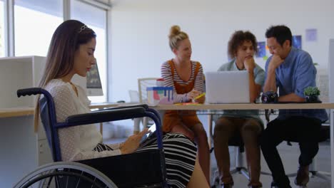 Side-view-of-young-Caucasian-disabled-female-working-on-digital-tablet-against-three-business-people
