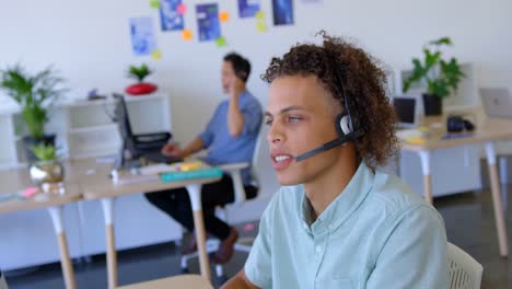 Young-mixed-race-male-executive-talking-on-headset-at-desk-4k