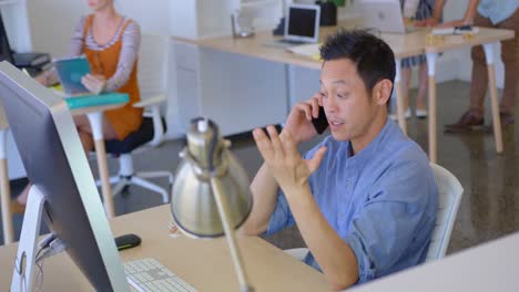 Young-Asian-business-male-executive-talking-on-mobile-phone-in-modern-office-4k