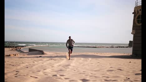 African-American-male-runner-jogging-on-beach-in-the-sunshine-4k